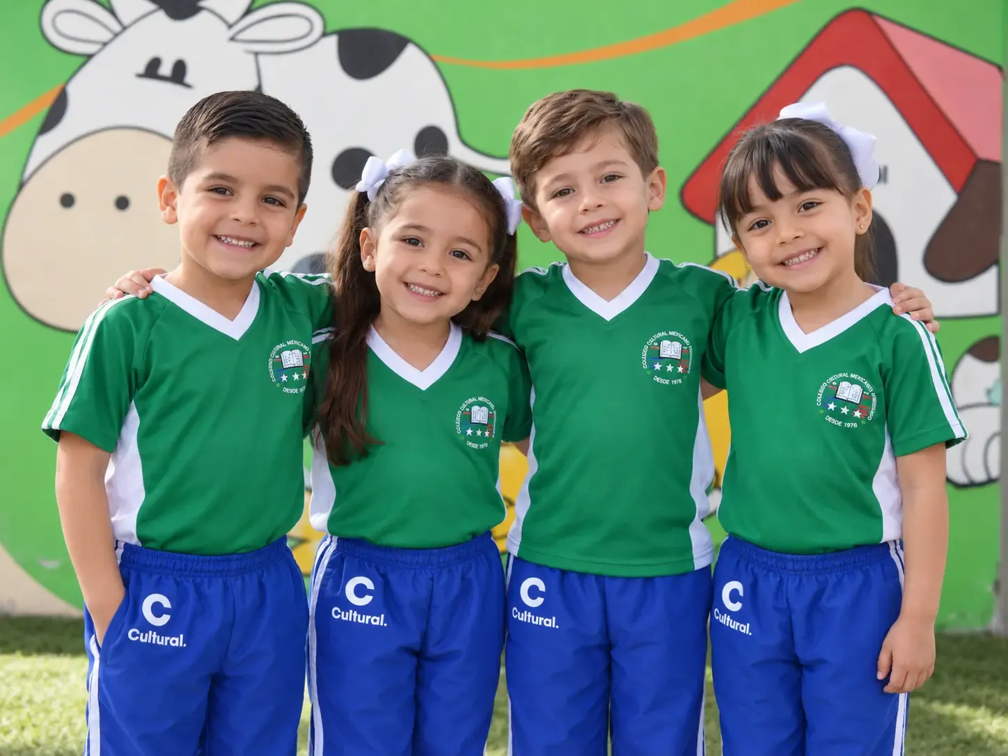 Cuatro alumnos de preescolar del CCMA sonríen juntos con el uniforme escolar